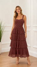Front view of model wearing burgundy polka dot tiered midi dress