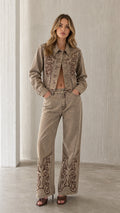 Front view of model wearing khaki embroidered denim jacket and pants set
