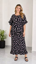 Full front view of women's black floral print tie-neck top and ruffle maxi skirt two-piece set