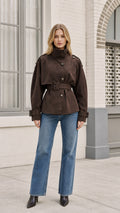 Front view of model wearing brown faux suede trench jacket with blue jeans
