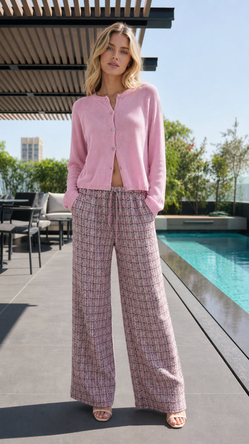 Model wearing pink knit cardigan and patterned wide-leg pants by pool, front view