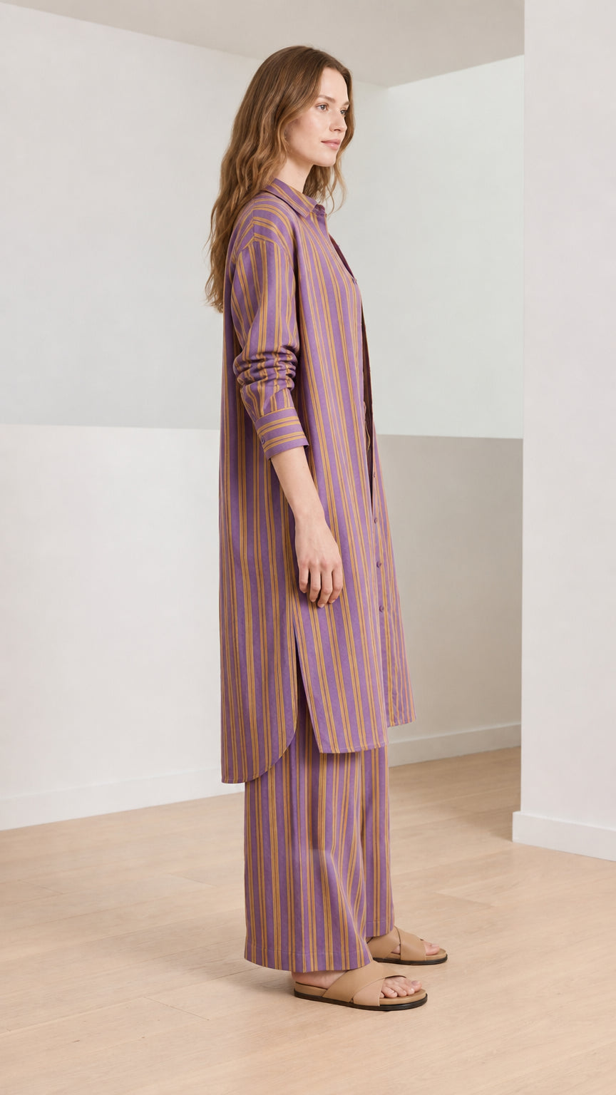 Woman wearing purple striped longline shirt and wide-leg pants side view