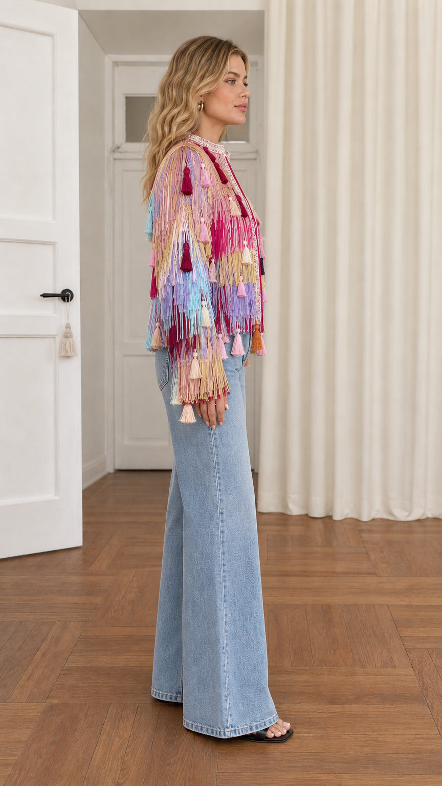 Side profile of model in colorful boho fringe and tassel statement jacket