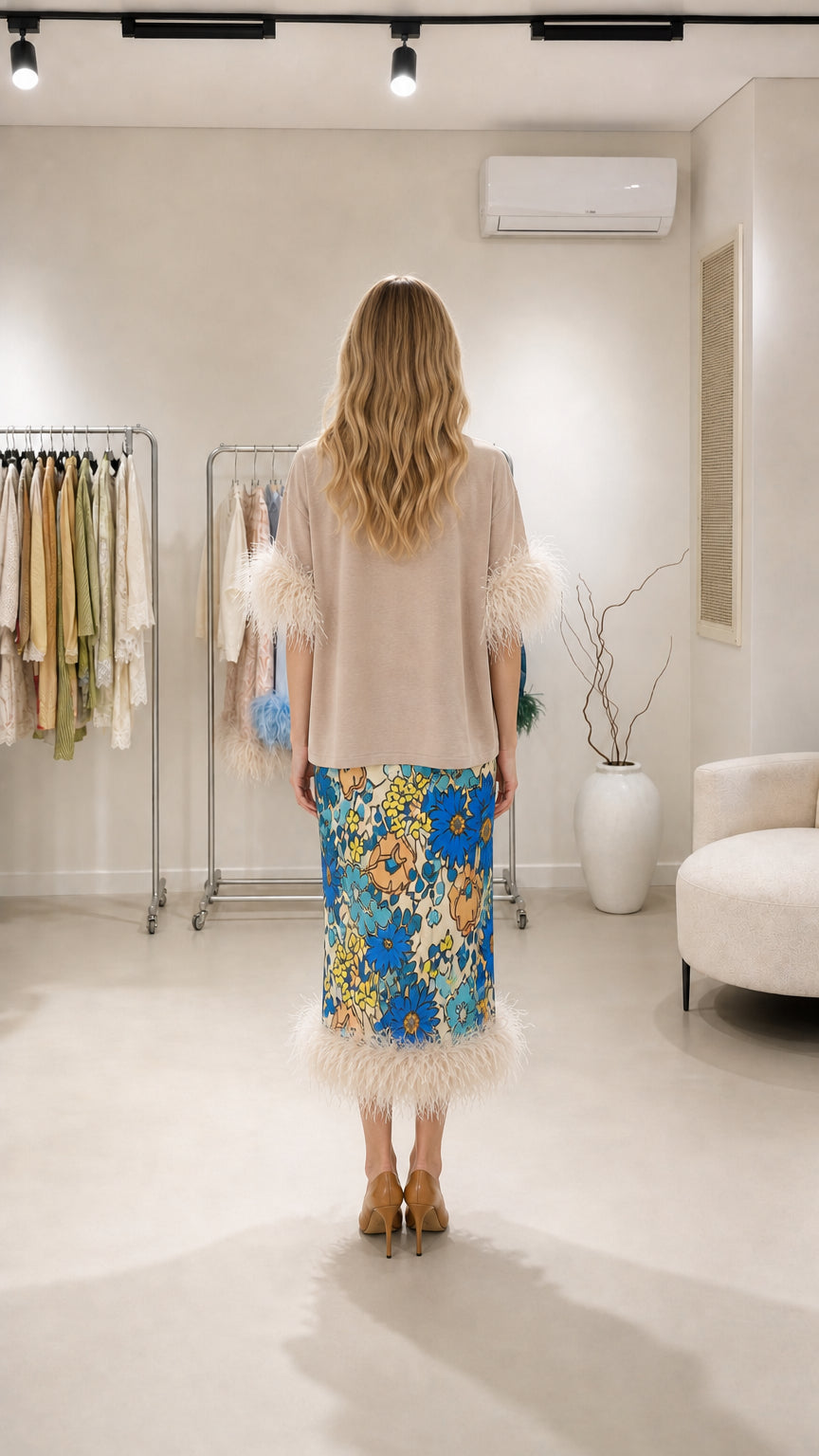 Back view of model wearing beige set with feather accents