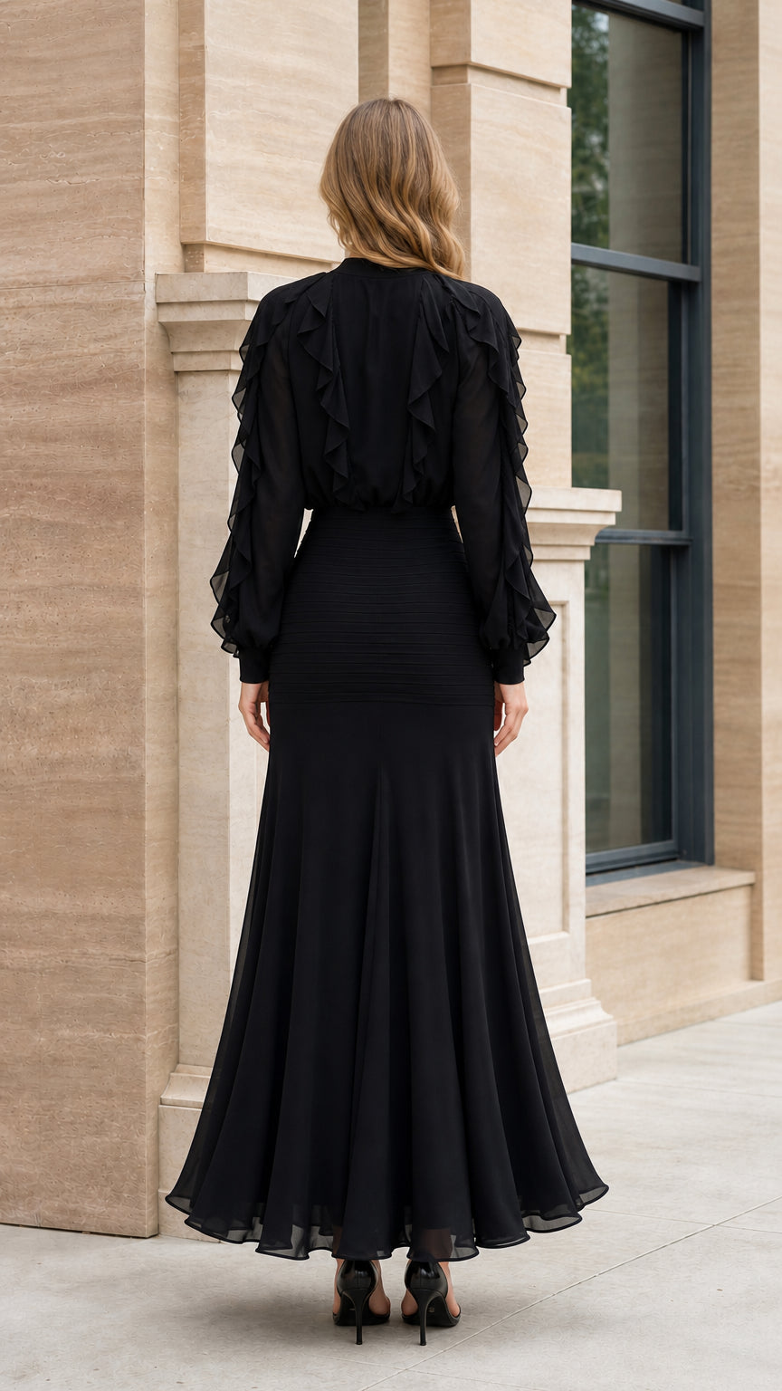 Back view of model showcasing flowing trumpet hem of black dress