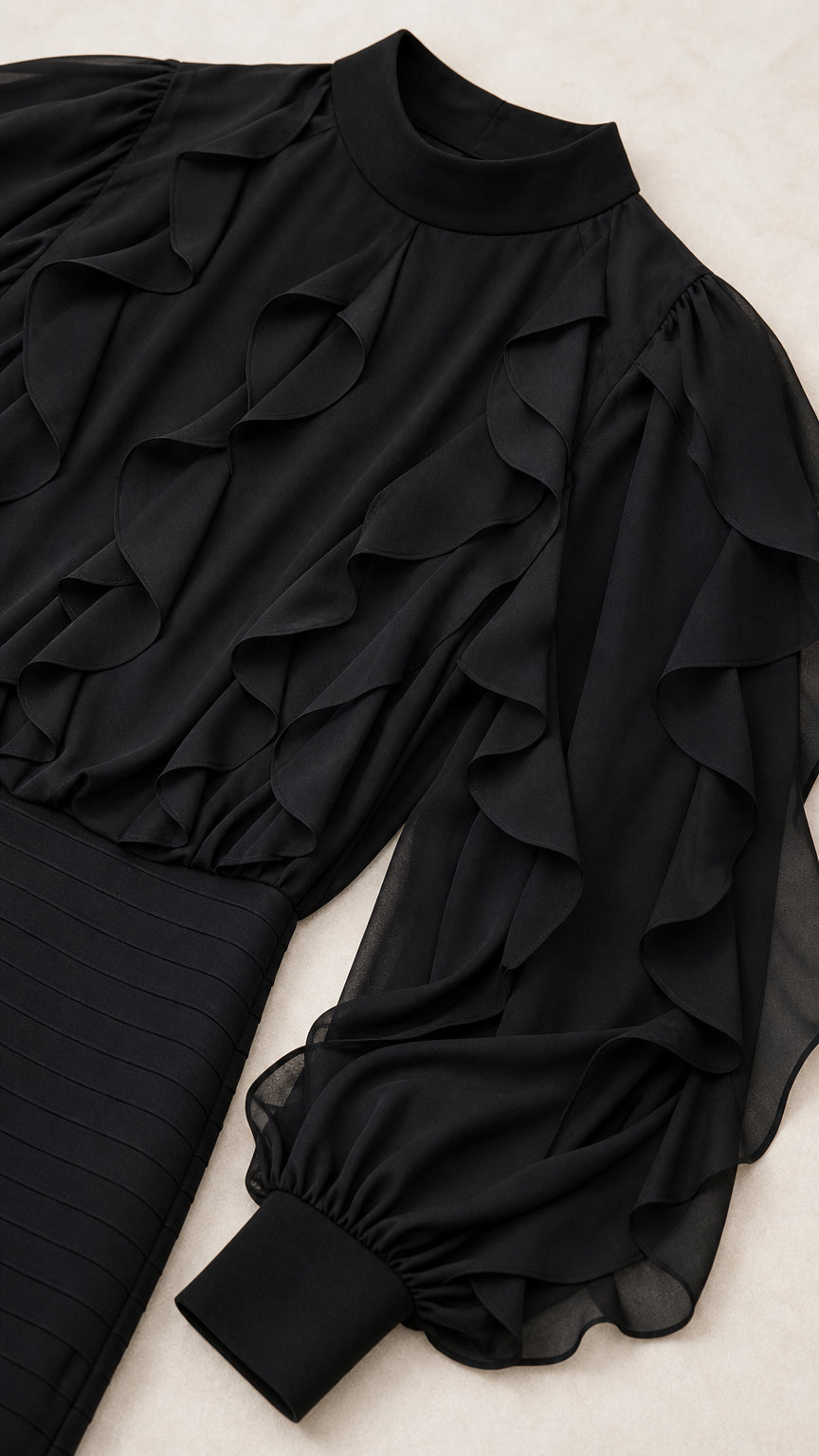 Close-up detail of mock neck, bodice ruffles, and banded cuffs on black dress