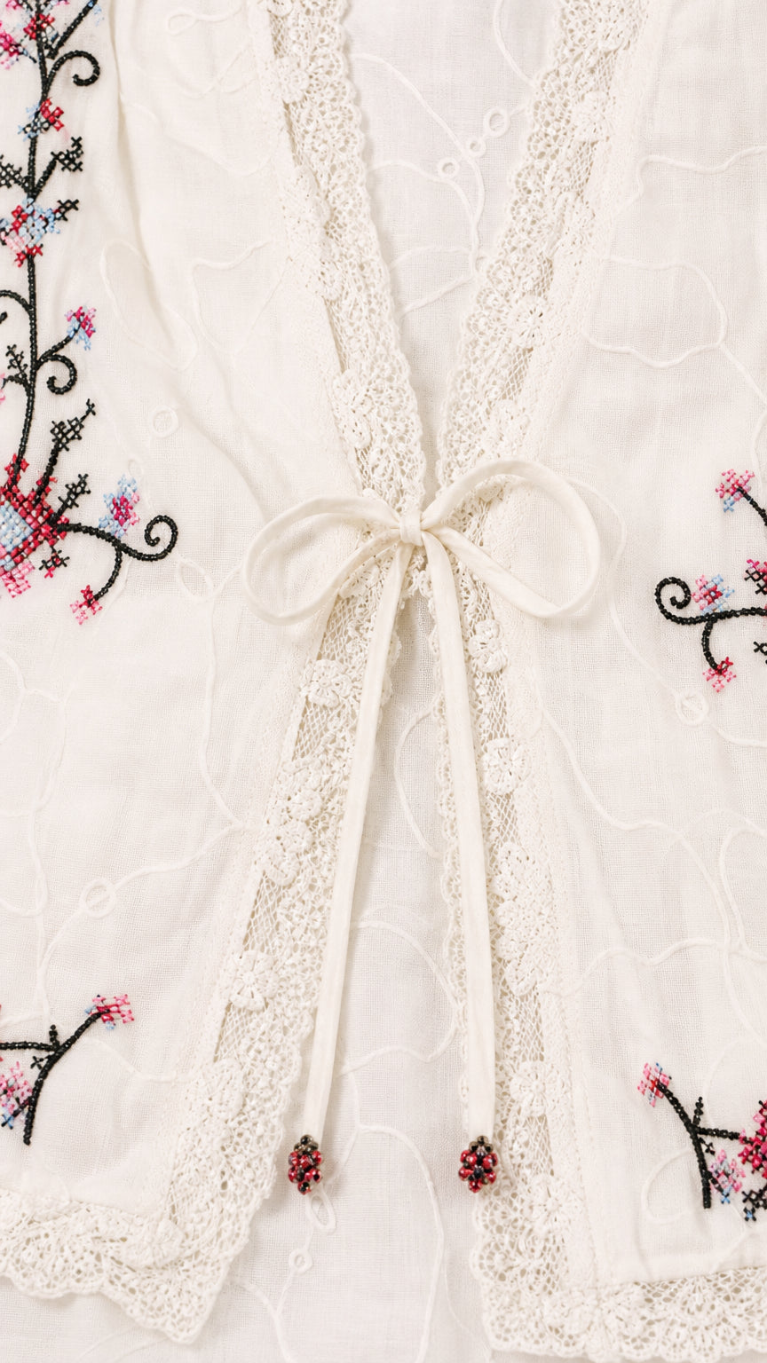 Close-up of jacket tie closure and floral embroidery details