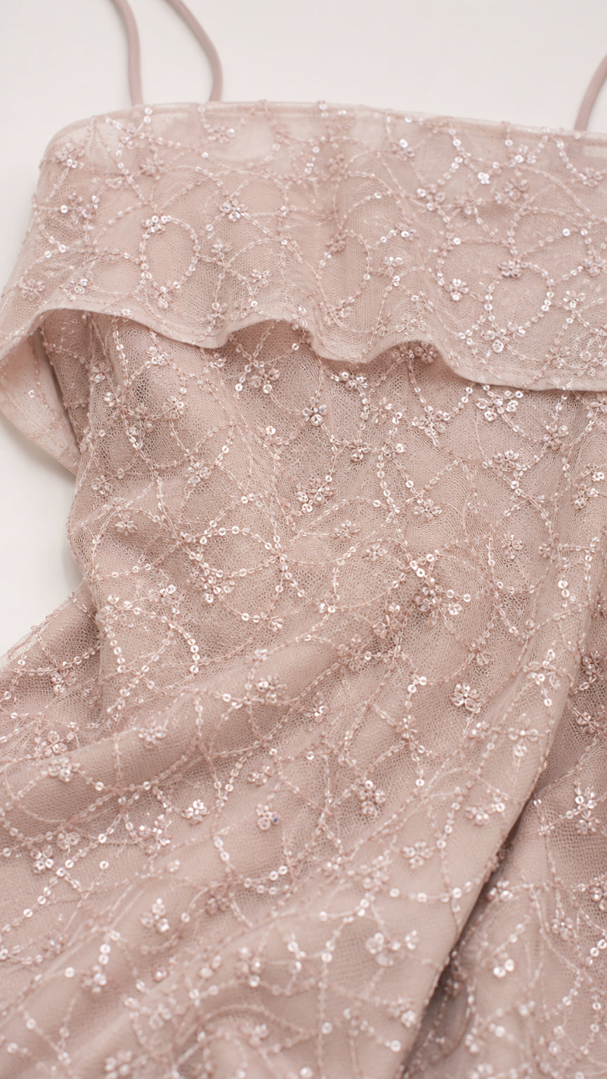 Close-up detail of dusty rose sequin lace fabric and folded neckline embellishment