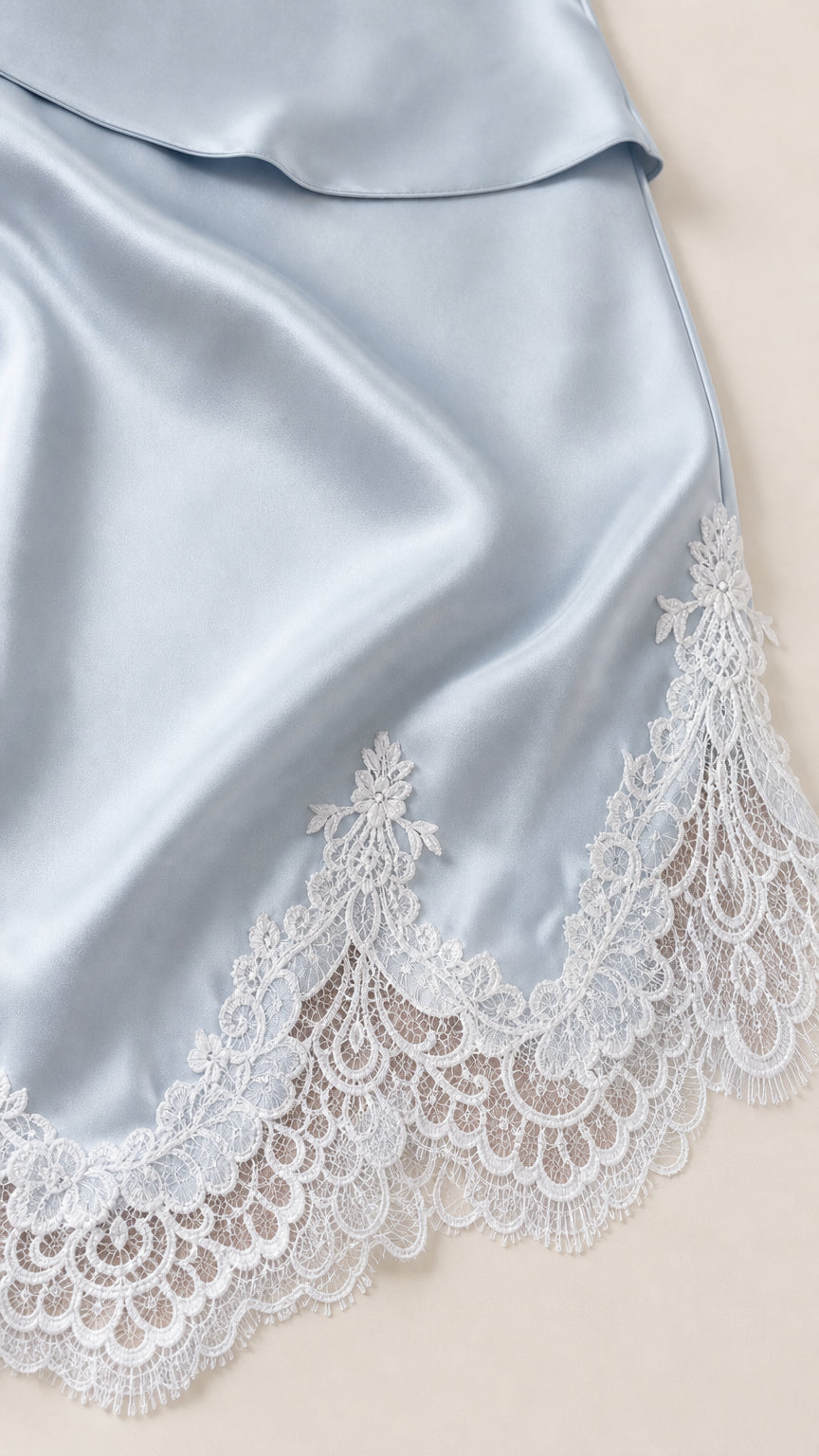 Close-up detail of light blue satin fabric and floral eyelash lace hem