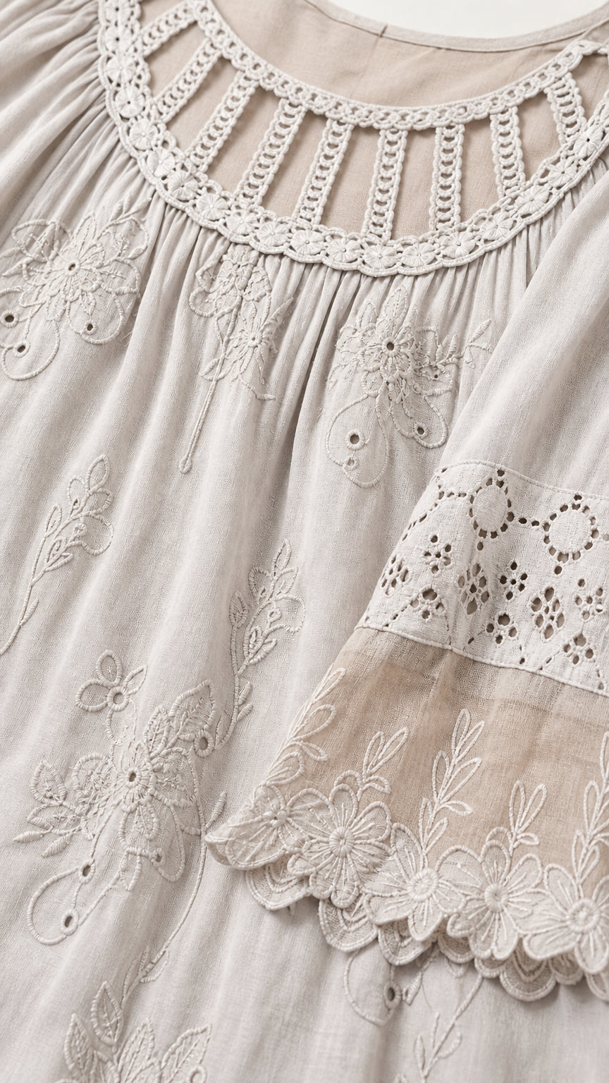 Close-up detail of cut-out neckline and floral embroidery on light grey top