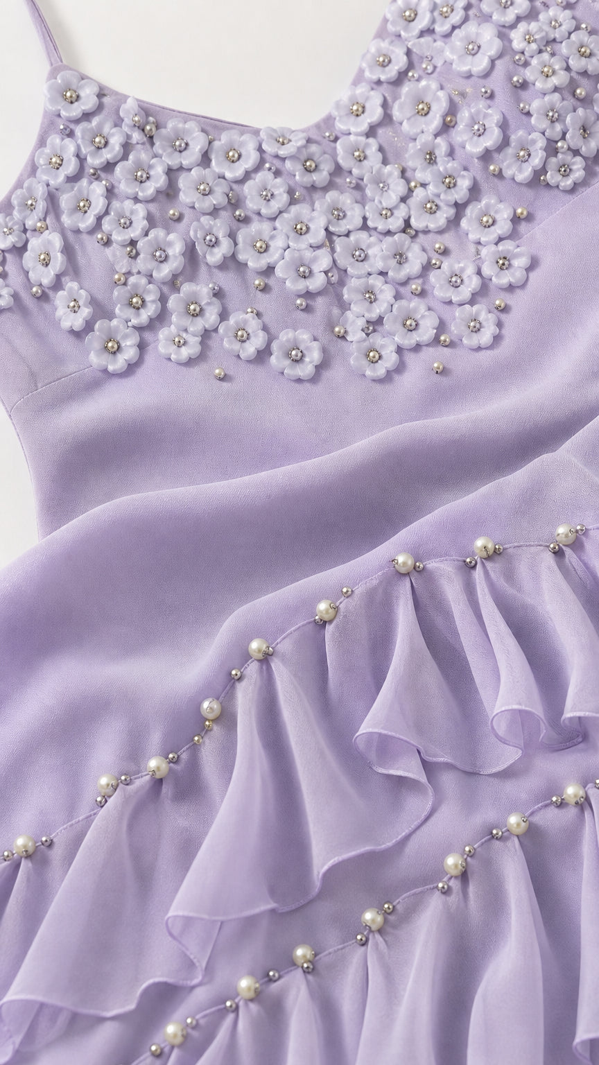 Close-up detail of 3D floral appliques and pearl-accented ruffled hemline