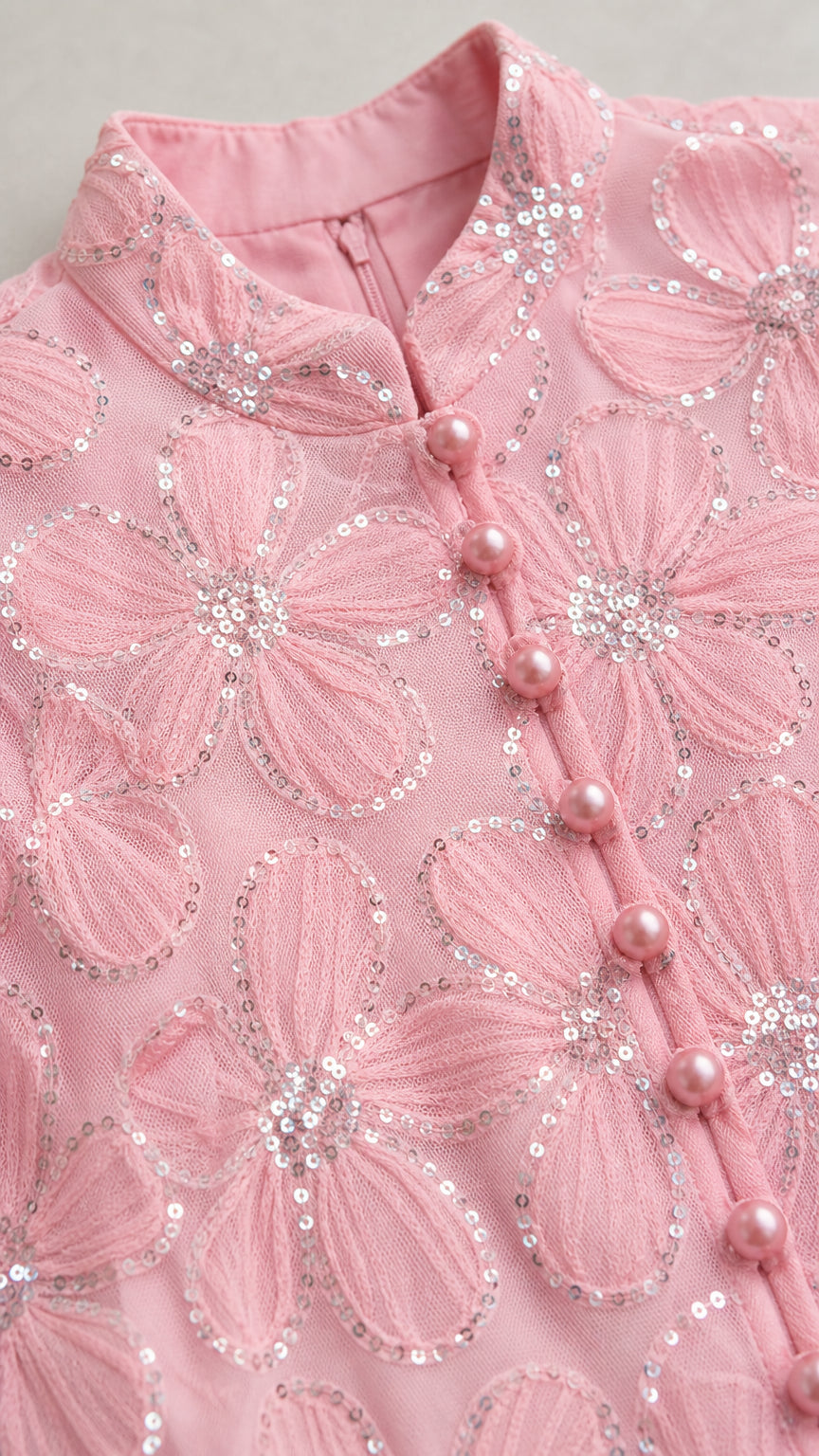 Close-up detail of mock neck, buttons, and sequin floral embroidery