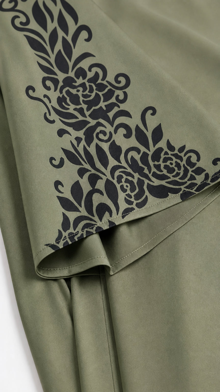 Close-up detail of black ornate floral border print on Sage Green woven fabric