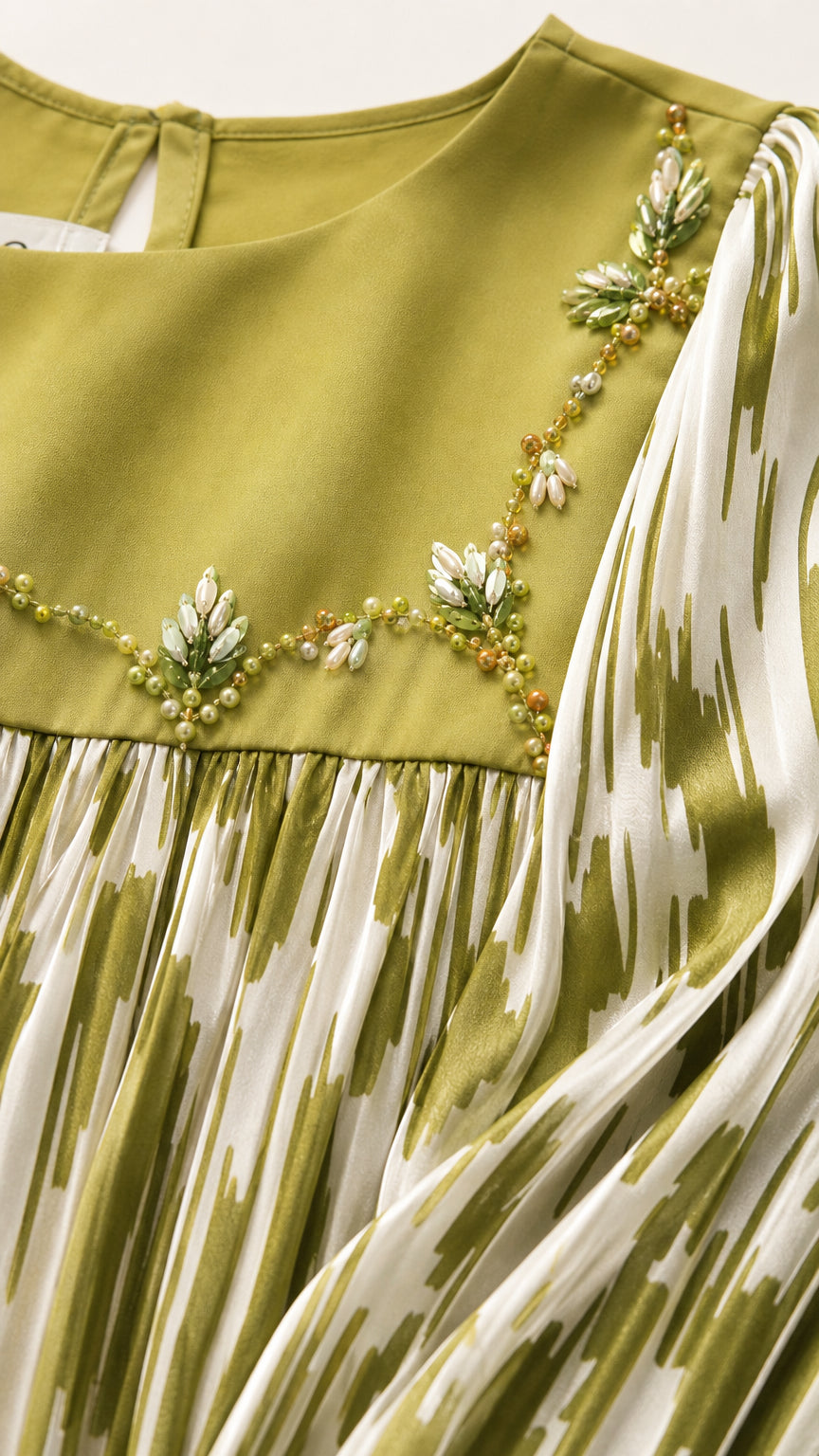 Close-up detail of embroidered floral beadwork on yoke and pleated print fabric