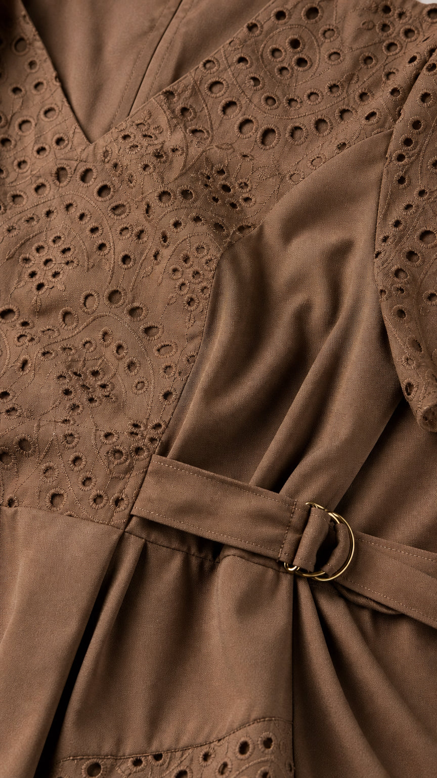 Close-up detail of mocha brown eyelet embroidery and side belt buckle