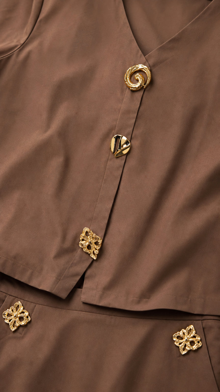 Close-up of brown blouse fabric showing unique sculptural gold-tone buttons