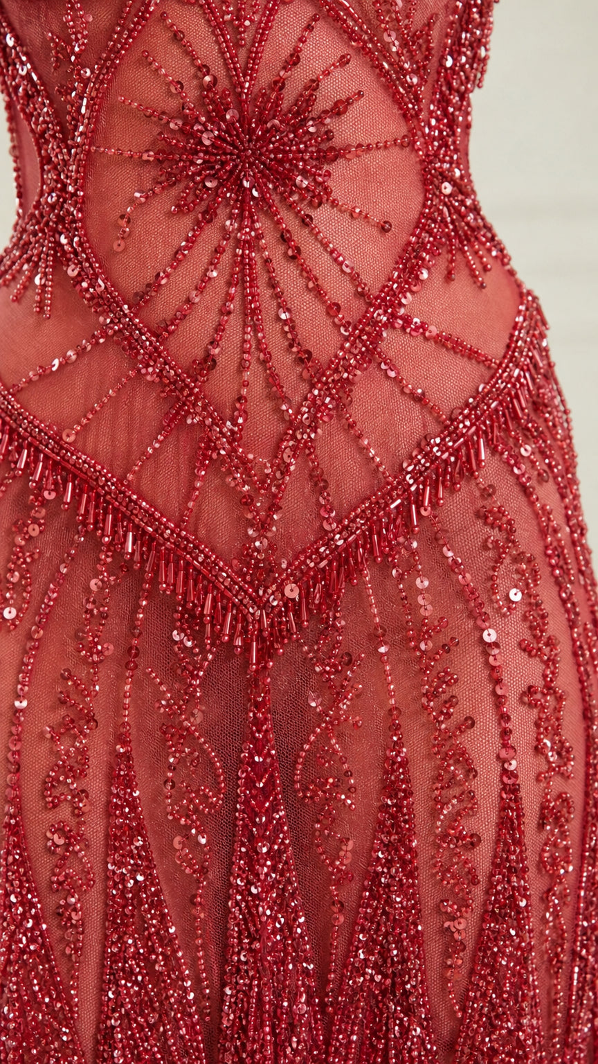 Close-up of intricate geometric beadwork and sequins on red dress
