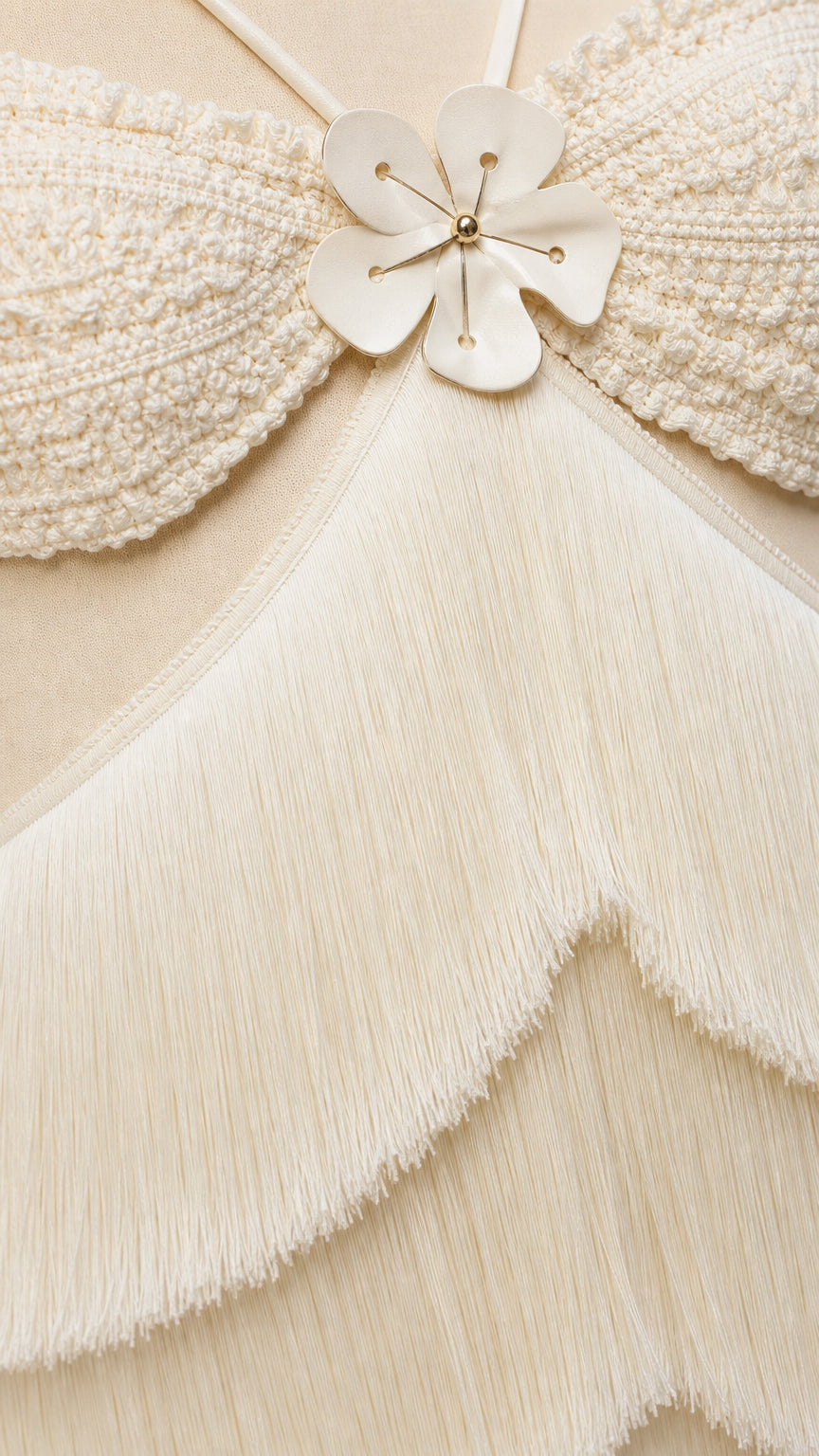 Close-up detail of textured bodice with floral applique and tiered fringe layers