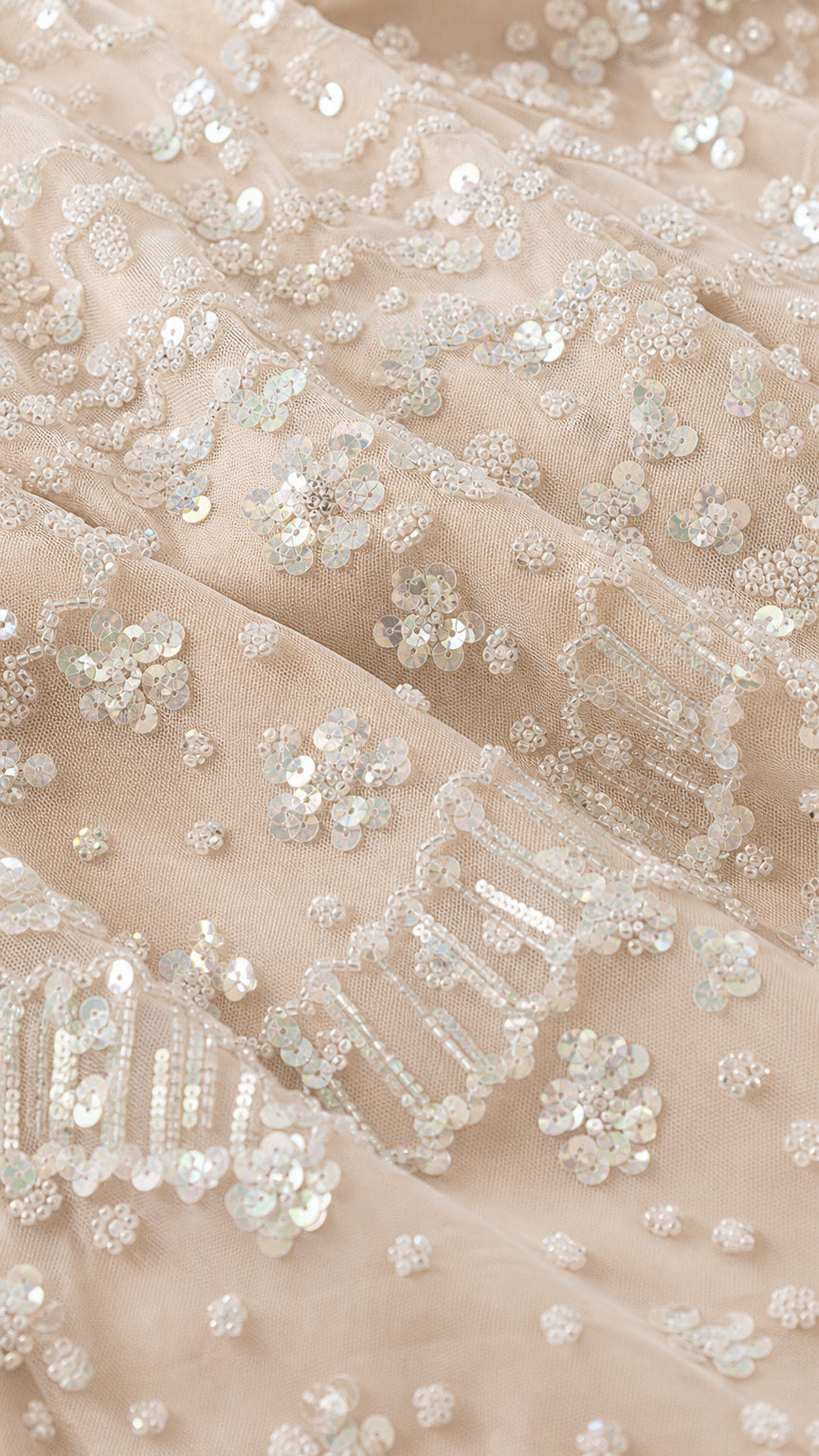 Close-up detail of intricate sequin and bead embroidery on mesh fabric