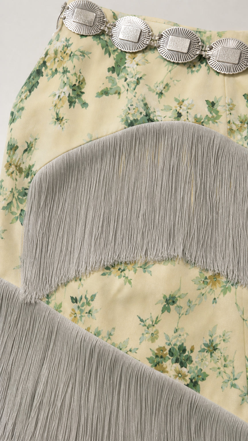 Close up detail of floral print fabric with cascading fringe trims and belt detail