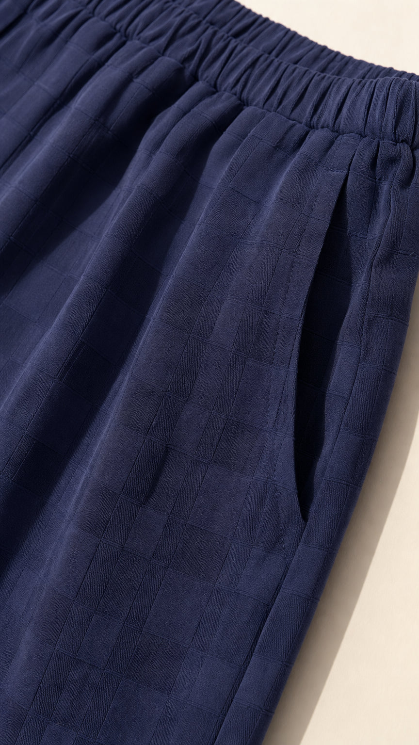 Close-up of navy textured fabric, elastic waistband, and pocket detail
