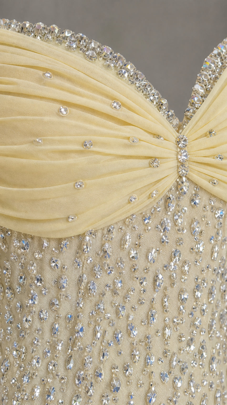 Close-up detail of crystal beadwork and draped neckline on yellow gown