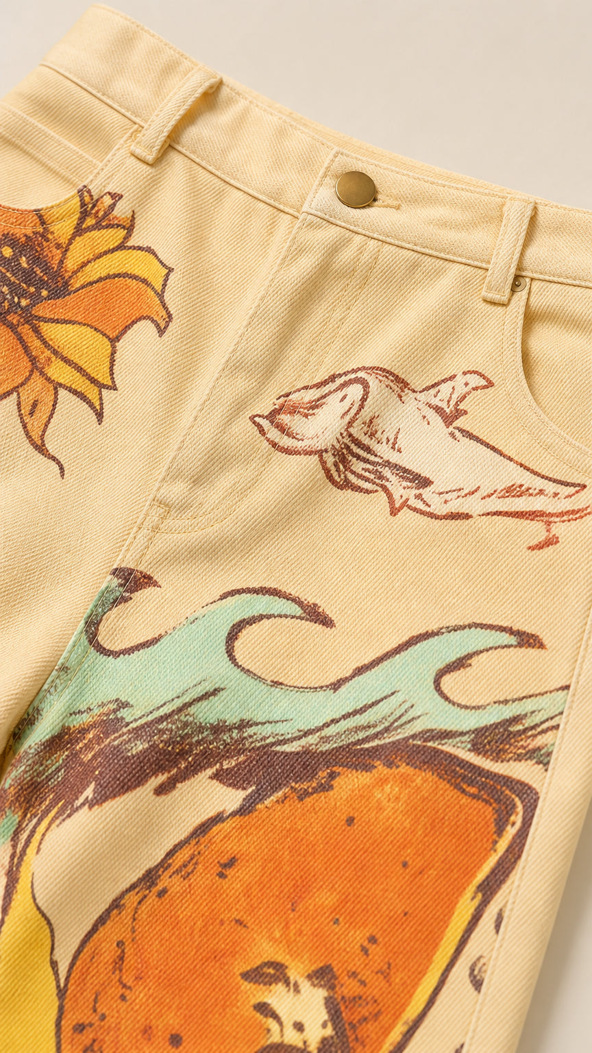 Close-up detail of yellow corduroy fabric, waistband, and artistic nature print