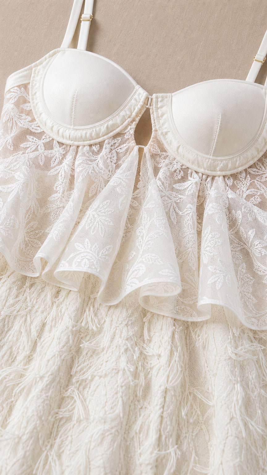 Close-up detail of white bustier cups, lace peplum ruffle, and feather texture