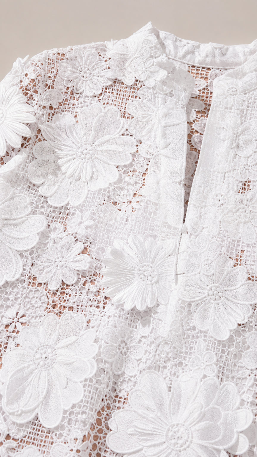 Close-up detail of white floral lace fabric and neckline
