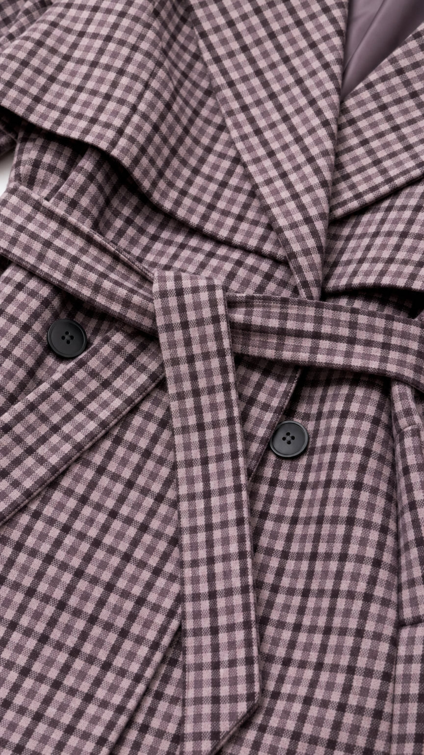 Close-up of fabric, buttons, and belt on plaid trench coat