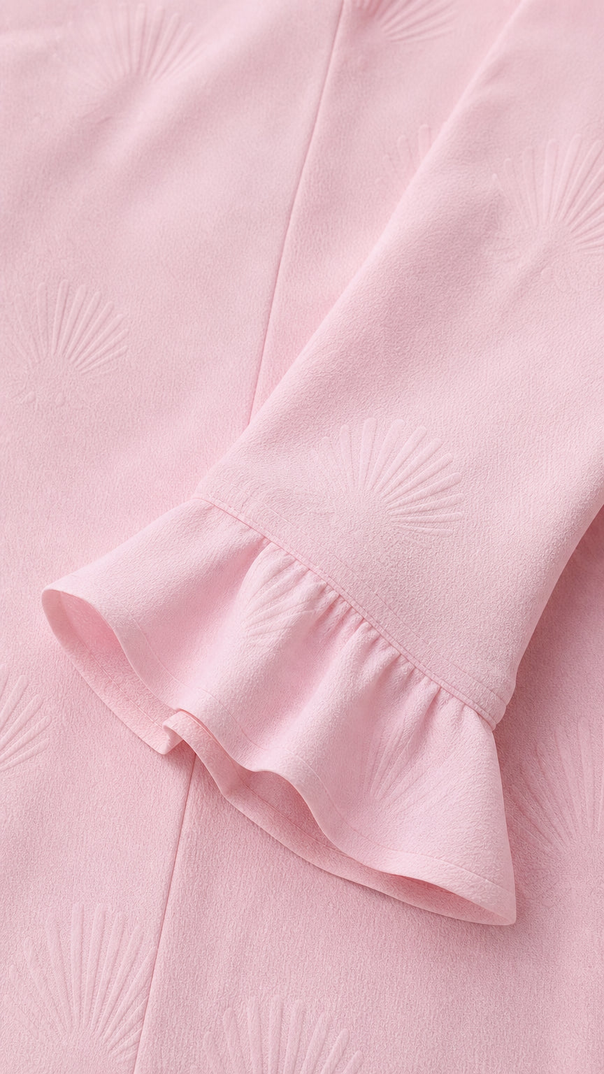 Close-up of blush pink textured jacquard fabric and ruffled sleeve cuff