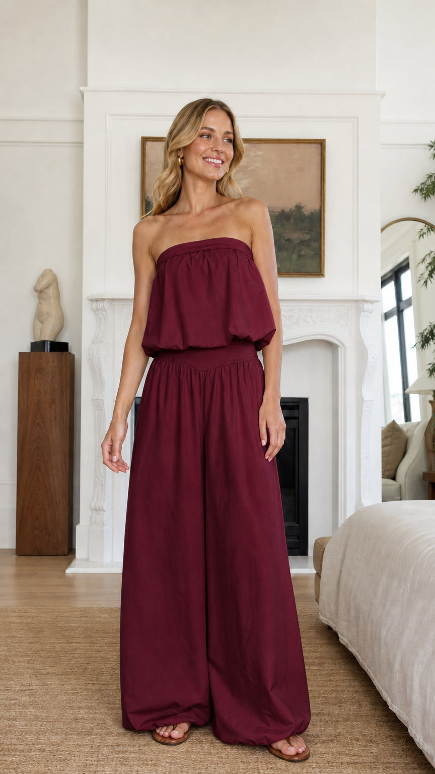Model wearing burgundy strapless ruffle crop top and wide leg pants set
